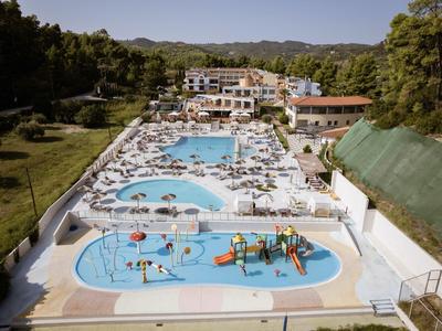 Amplia área de piscina del hotel con tumbonas, piscina infantil y parque acuático, rodeada de naturaleza.