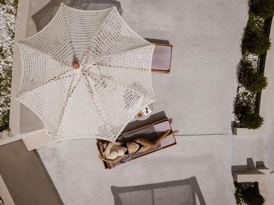 Blick von oben auf eine Liege mit Sonnenschirm und einer Person am Poolbereich.