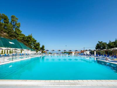 Großes, klares Schwimmbecken mit Liegestühlen und Sonnenschirmen unter blauem Himmel.