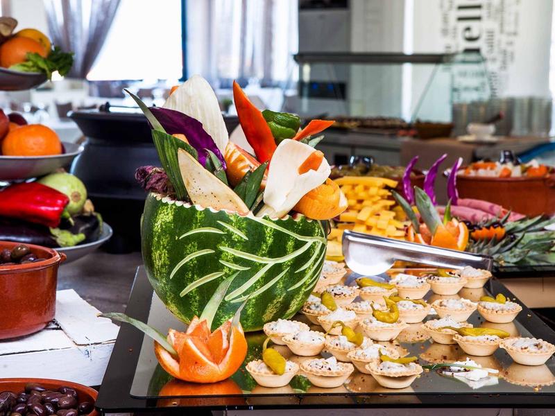 Bandeja con frutas talladas artísticamente y pequeños bocados en el buffet del restaurante.