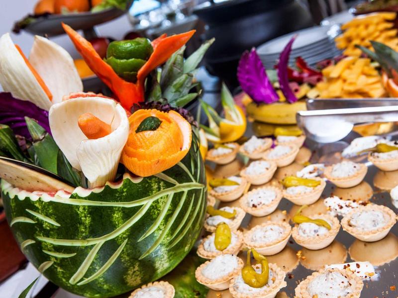 Aperitivos dulces en un buffet decorado con frutas tropicales festivas.