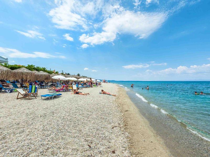Playa con tumbonas y sombrillas junto al mar bajo un cielo parcialmente nublado.