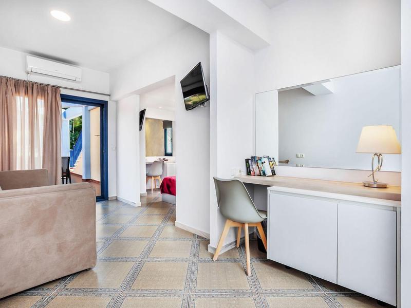 Habitación de hotel amueblada con sofá, gran espejo y escritorio con silla.