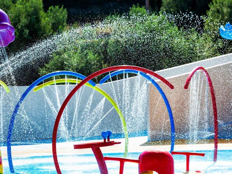 Juego de agua colorido con varios anillos de rociado y fuentes en un parque acuático