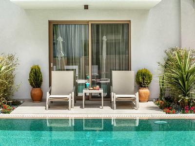 Dwa leżaki z stolikiem pomiędzy nimi przed przesuwnymi drzwiami szklanymi przy basenie.