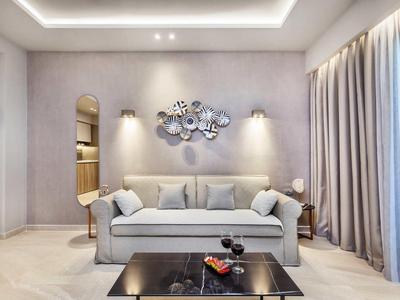 Nowoczesny salon z szarą sofą, dekoracją ścienną i dużym oknem z zasłonami.