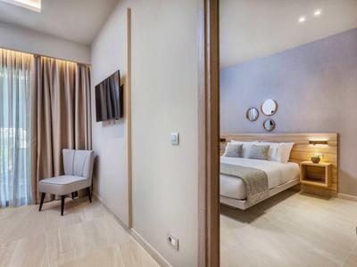 Nowoczesny pokój hotelowy z łóżkiem podwójnym, stolikiem nocnym, krzesłem i telewizorem na ścianie.