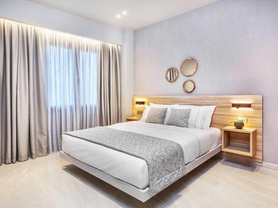 Nowoczesny pokój hotelowy z dużym łóżkiem, szarymi zasłonami i dekoracyjnymi panelami ściennymi.