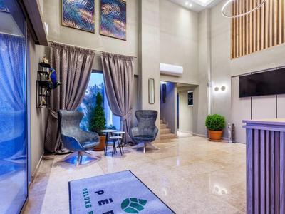 Nowoczesne lobby hotelowe z częścią wypoczynkową, dużymi oknami i jasną marmurową podłogą.