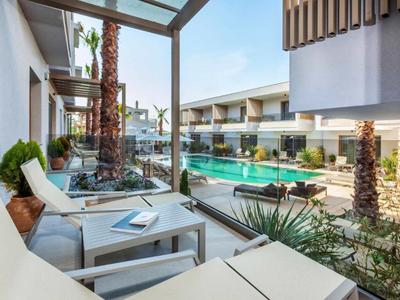 Chambre d'hôtel moderne avec balcon, vue sur la piscine et design tropical.