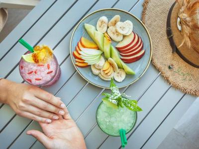 Deux personnes se tenant la main près de boissons et d'une assiette de fruits frais sur une table grise.