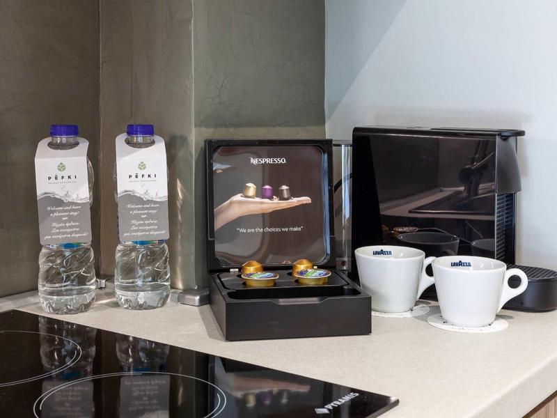 Butelki wody, ekspres do kawy i filiżanki na blacie kuchennym.