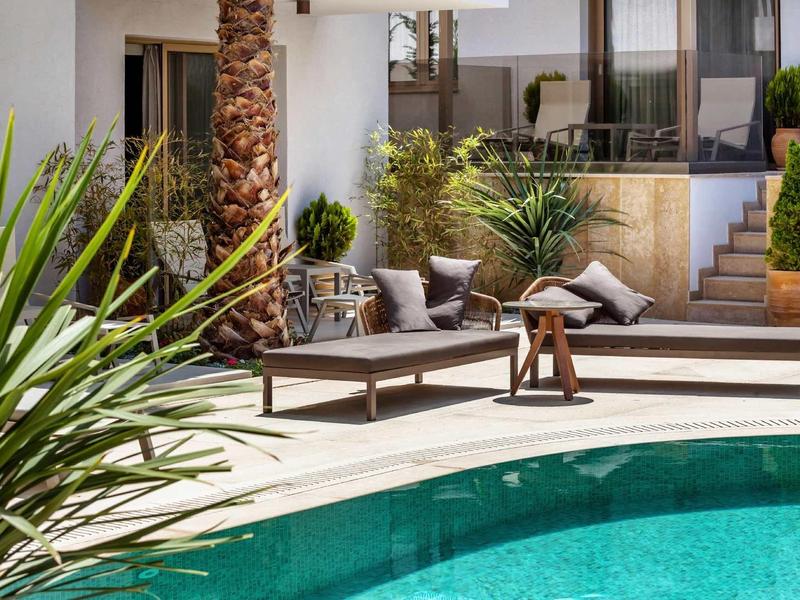 Nowoczesny basen z leżakami, roślinami i jasnymi ścianami.