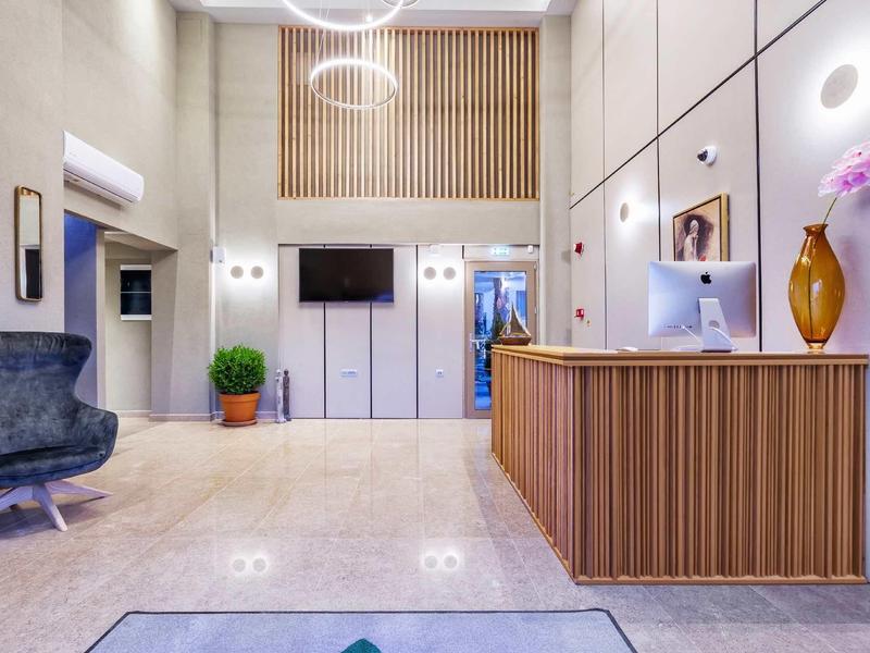 Nowoczesna recepcja hotelowa z jasnym wnętrzem, fotelem i ladą recepcyjną.