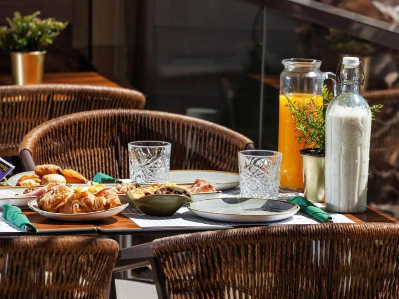 Przytulne śniadanie na zewnątrz z rogalikami, sokiem i mlekiem na drewnianym stole.