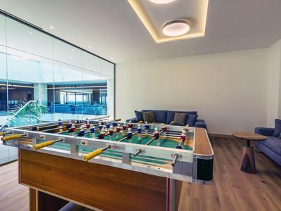 Moderner Raum mit Kickertisch, Sofas und großen Glasfenstern mit Blick auf Außenbereich.