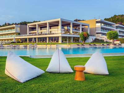 Modernes Hotel mit Pool und bequemen Sitzsäcken auf gepflegtem Rasen unter blauem Himmel