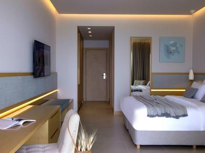 Modernes Hotelzimmer mit Doppelbett, Schreibtisch, Fernseher und indirekter LED-Beleuchtung.