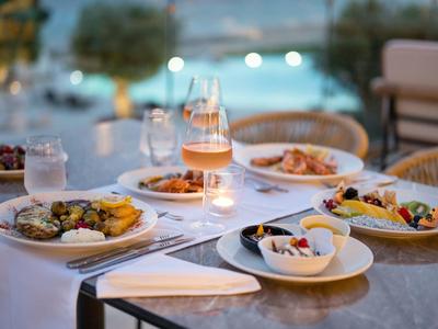 Ein gedeckter Tisch mit bunten Speisen, Gläsern und Kerzen in gemütlicher Atmosphäre am Abend.
