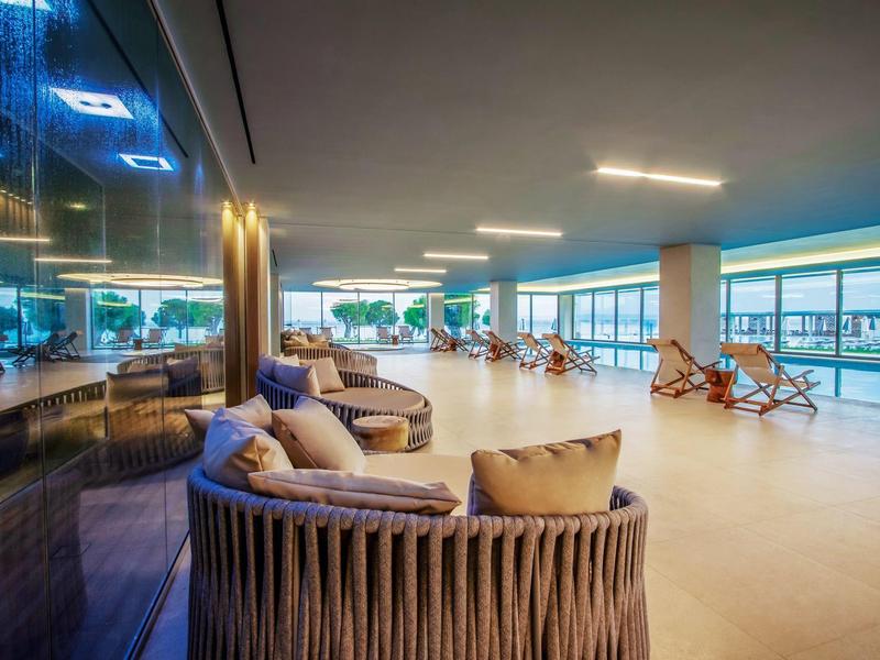 Moderner Lounge-Bereich mit gemütlichen Sitzmöbeln, Holzverkleidung und großen Panoramafenstern.