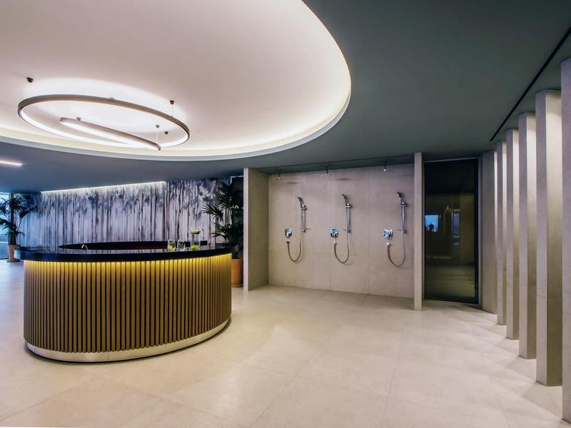 Moderner Lounge-Bereich mit rundem Tresen, sanfter Beleuchtung und stilvollen Duschstationen im Hintergrund.