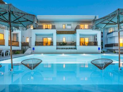 Piscine d'hôtel moderne avec chaises longues et parasols sous un ciel clair.