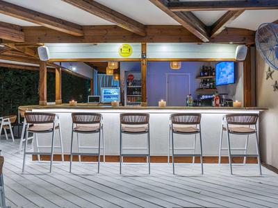 Bar extérieure moderne avec tabourets et comptoir éclairé sous un toit en bois.