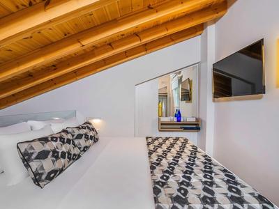 Chambre confortable avec plafond incliné, lit double, couvre-lit à motif et miroir mural.