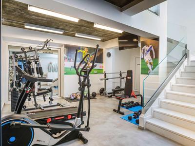 Modern gym with workout equipment and staircase in bright interior.