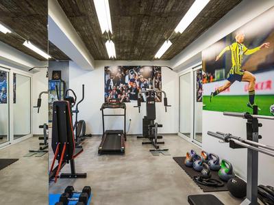 Modern gym with various workout equipment and sports pictures on the walls.