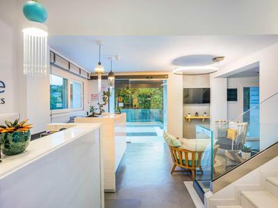 Intérieur d'hôtel lumineux et moderne avec comptoir, coin salon et vue sur un espace extérieur verdoyant.