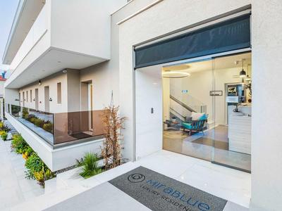 Modern hotel corridor with glass railing and view into restaurant through open sliding door.