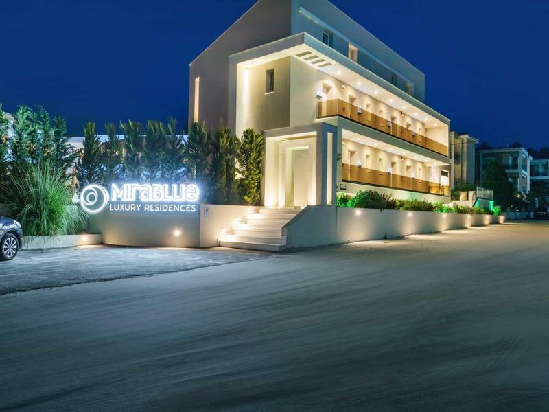 Bâtiment d'hôtel moderne éclairé la nuit avec lignes épurées et palmiers.