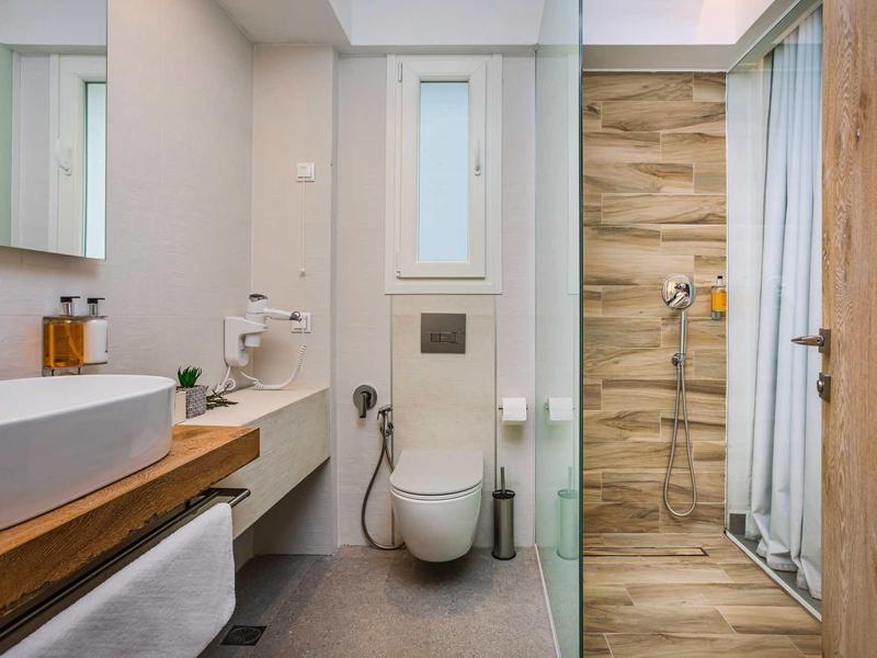 Salle de bain moderne avec lavabo, toilettes et douche avec porte en verre et carrelage en bois.