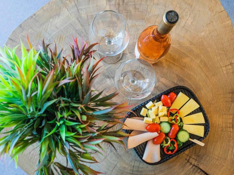 Assiette de fromages et charcuterie avec bouteille de vin et verres sur planche en bois à côté d'une plante