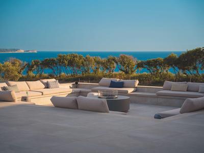 Große, moderne Terrasse mit bequemen Sitzmöbeln und Blick auf das blaue Meer.