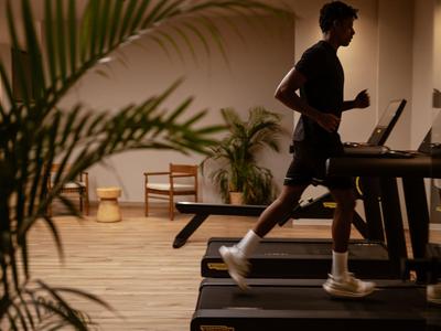 Ein Mann läuft auf einem Laufband in einem stilvollen Fitnessraum mit gemütlicher Beleuchtung.