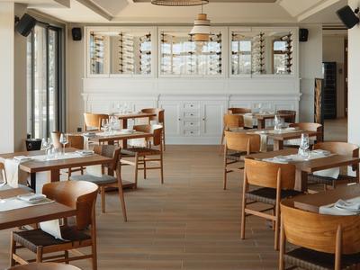 Modern eingerichteter Speisesaal mit Holzmöbeln und großen Fenstern in einem Hotel.