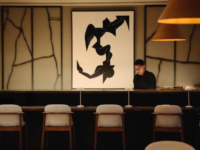 Moderne Hotelbar mit Holzstühlen, abstrakter Kunst und gedämpfter Beleuchtung.