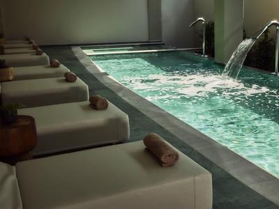 Overdekt zwembad met watervallen en ligstoelen met handdoeken in een rustige spa