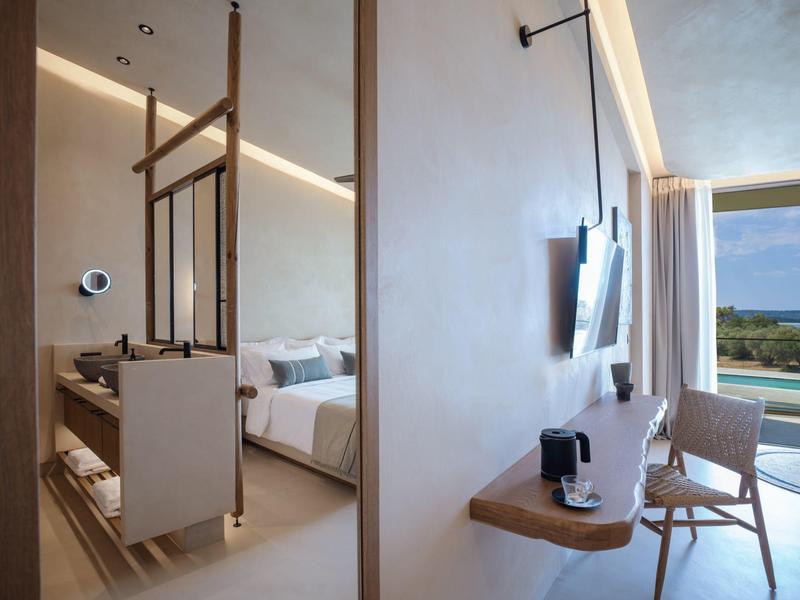 Modern hotelkamer met tweepersoonsbed, houten meubels en zeezicht.