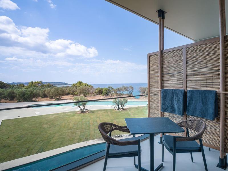 Balkon met tafel, stoelen en zeezicht onder een heldere lucht in een hotel.