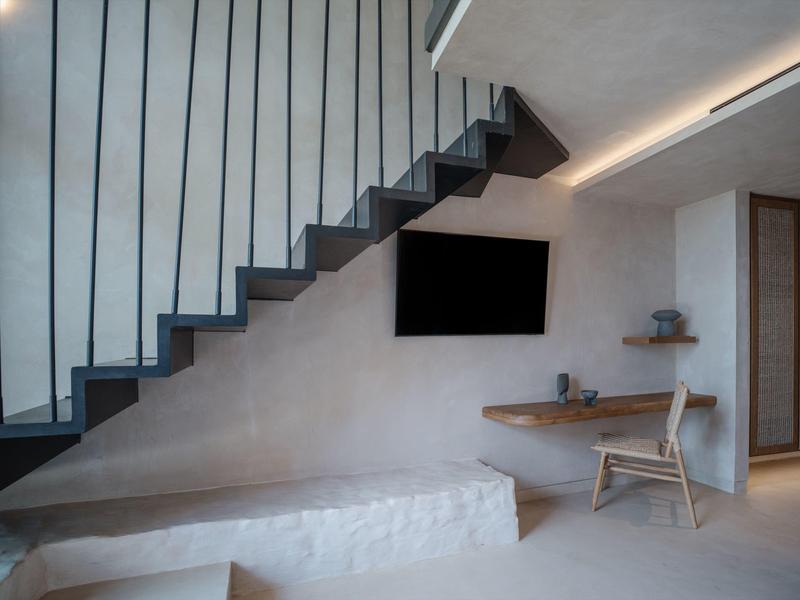 Moderne binnenruimte met trap, aan de muur gemonteerde tv en bureau onder de trap