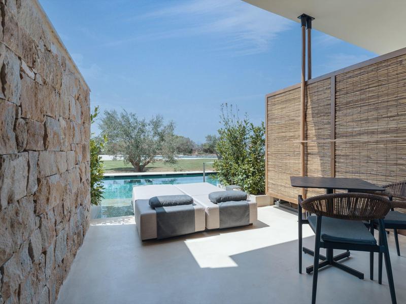 Moderne buitenruimte met zwembad, bank en tafel met stoelen, omgeven door natuur.