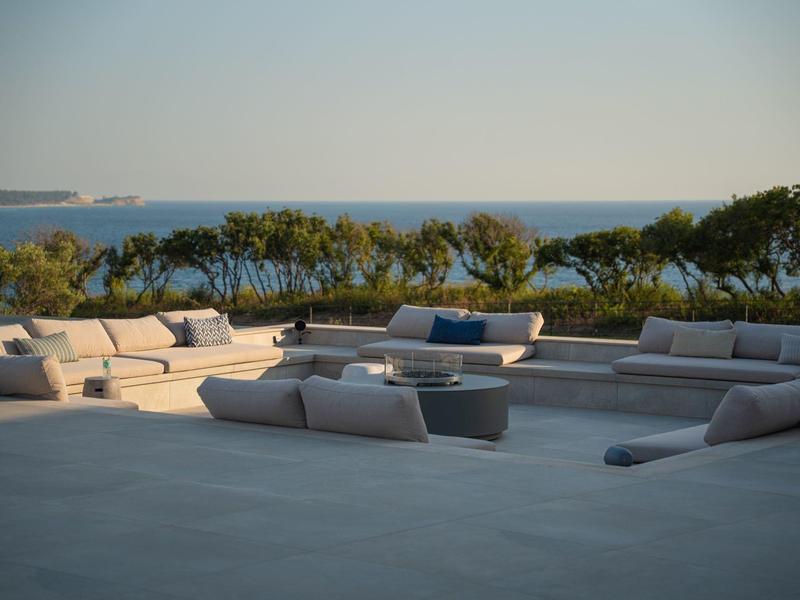 Groot terras met comfortabele banken en uitzicht op zee bij zonnig weer.