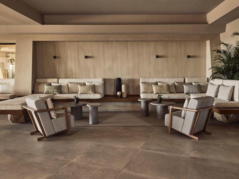 Moderne lounge met comfortabele fauteuils en banken in neutrale tinten en planten.