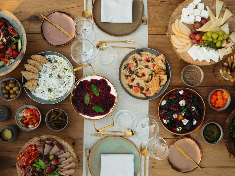 Divers gedekte eettafel met verschillende voorgerechten en drankjes in glazen.