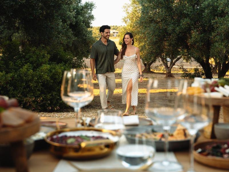 Stel loopt door een tuin met een gedekte tafel en wijn buiten.