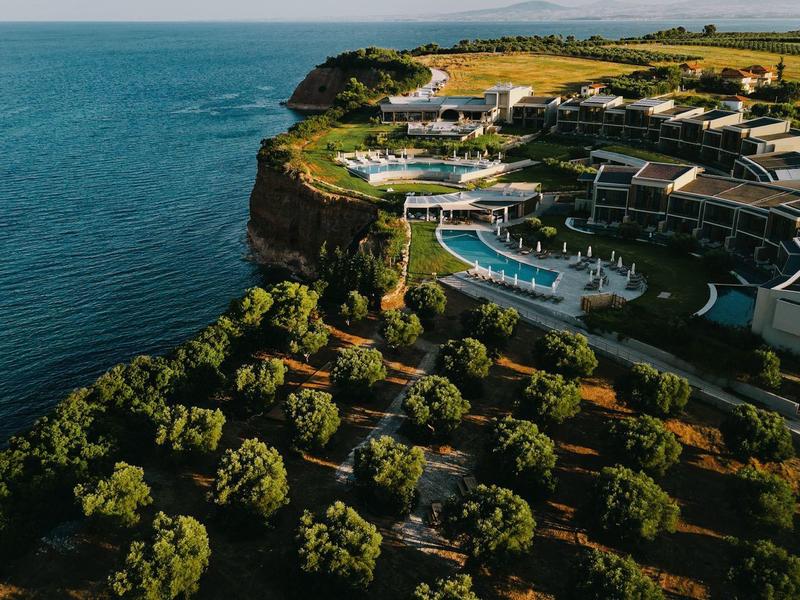 Luxe resort met zwembaden op een klif met uitzicht op de zee, omgeven door weelderig groen.