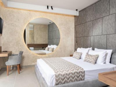 Nowoczesna sypialnia z dużym okrągłym lustrem, łóżkiem podwójnym i stylowymi szarymi akcentami.